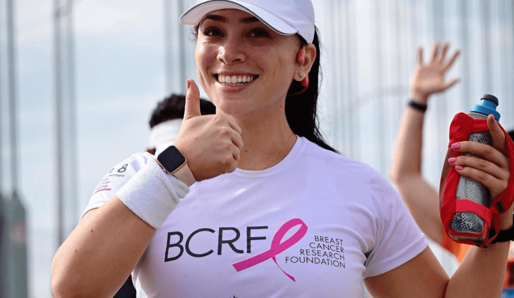 a team bcrf runner participates in a race wearing a bcrf shirt and giving a thumbs up