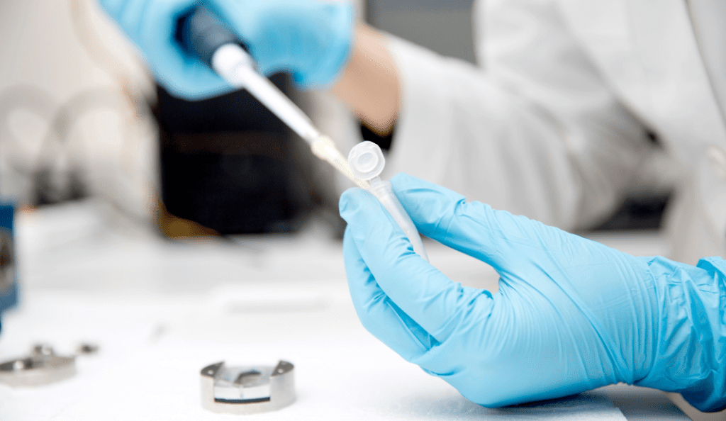 an image of two hands wearing blue gloves preparing a sample in a lab