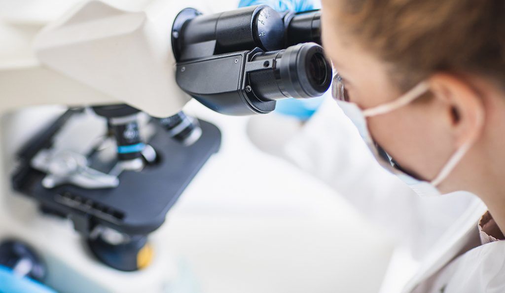 scientist looks at a microscope up close