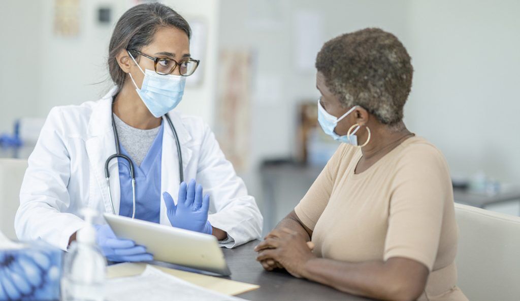 An older Black woman sits with her doctor for a consultation