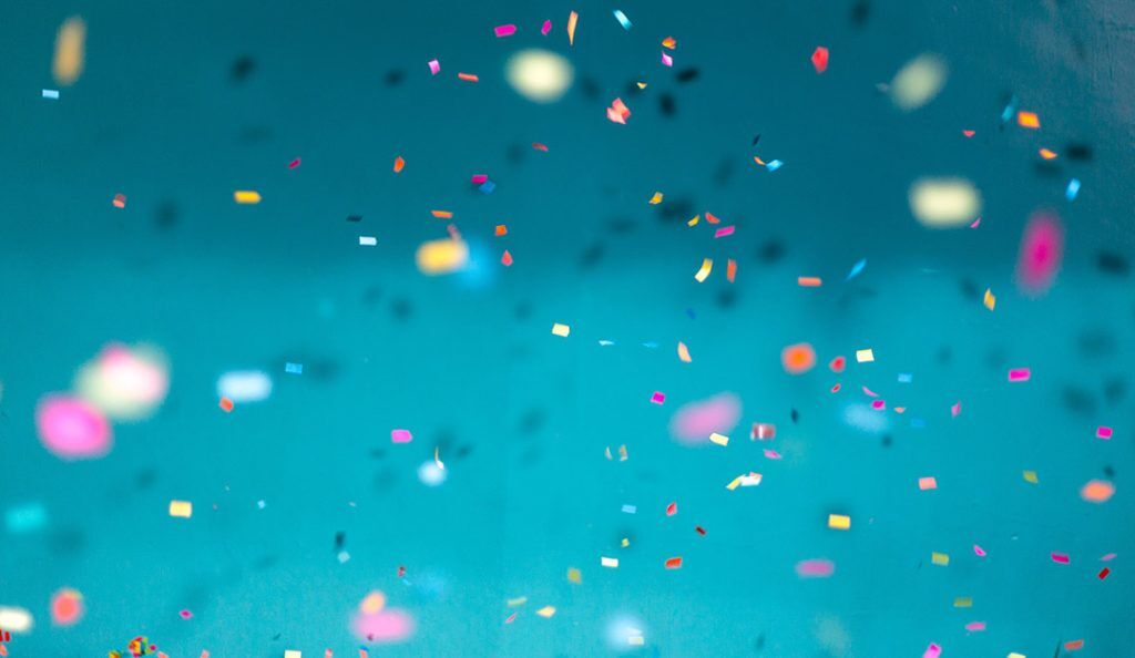 rainbow pieces of confetti against a teal blue background