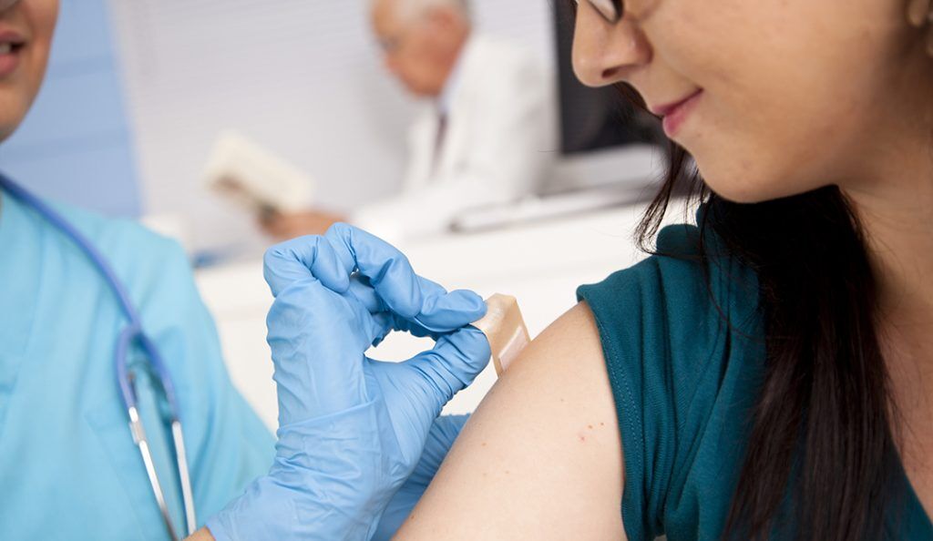 a doctor administers a bandage on a female patient after a shot