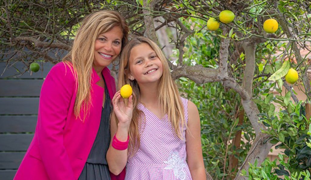 kim and brynne rhodes stand under a lemon tree wearing pink