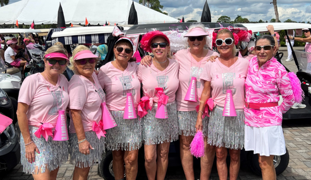 play for pink volunteers stand for a photo wearing pink shirts and silver sequin skirts at a play for pink event