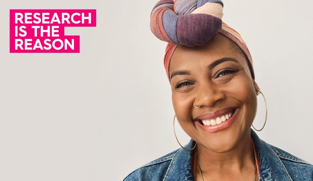 a portrait of miriam wearing a colorful head scarf and hoop earring smiling