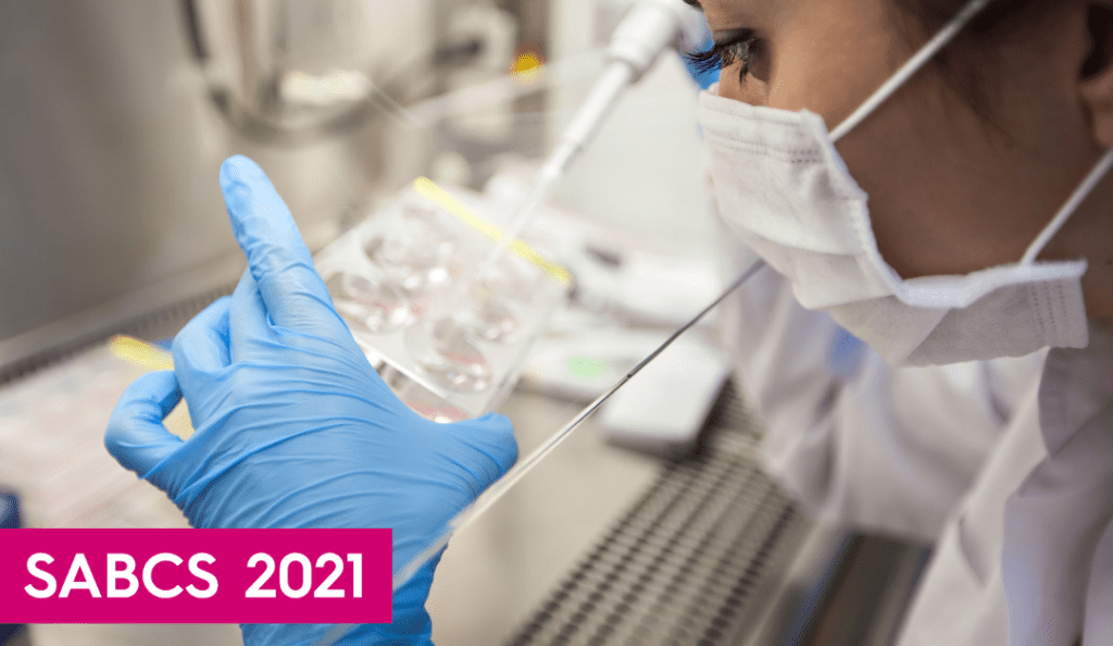 a woman in a lab wearing a mask and holds a pipette
