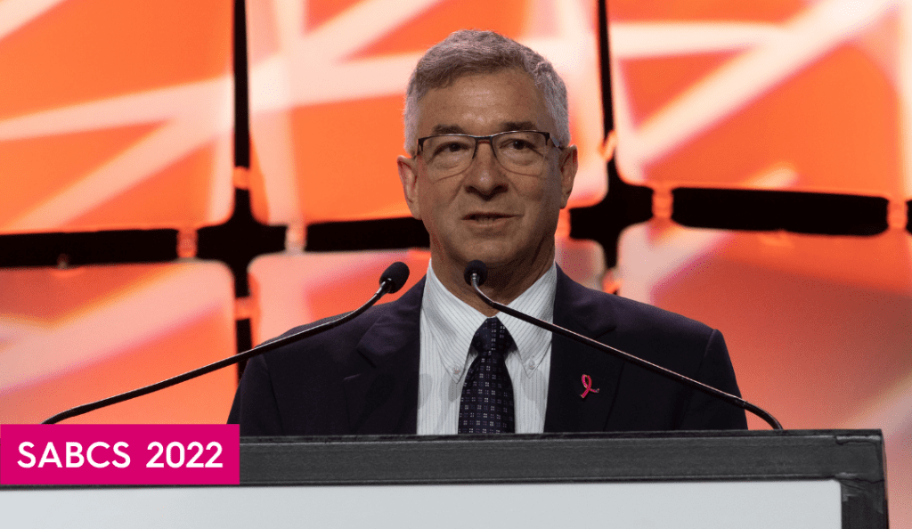 bcrf investigator dr. david rimm speaks at a podium at sabcs 2022 with an orange background behind him