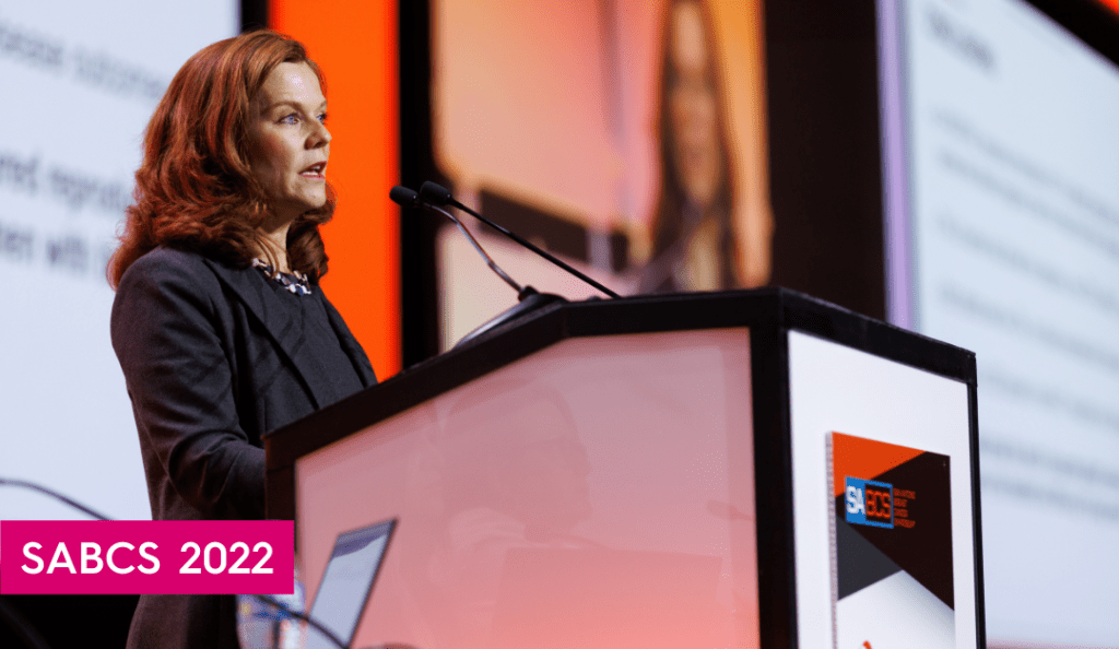 dr. ann partridge speaks at sabcs at a podium on a stage