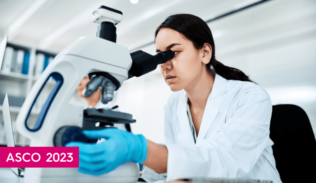 an asian woman wearing a lab coat looks at a microscope wearing blue gloves