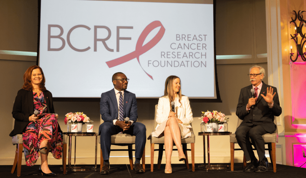 four BCRF researchers speak on a panel with the BCRF logo behind them on a stage
