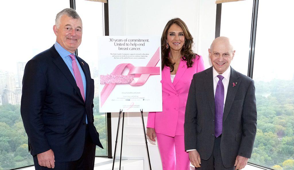 elizabeth hurley in a pink suit stands with dr. larry norton and william lauder