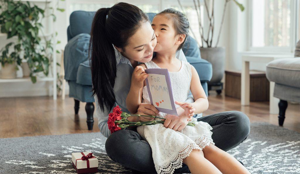 an asian woman embraces with her young daughter