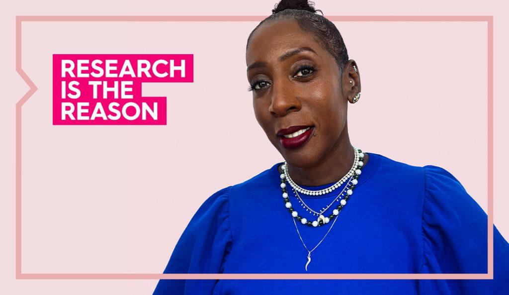 tracey poses for a photo smiling for the camera and wearing an ochre colored top