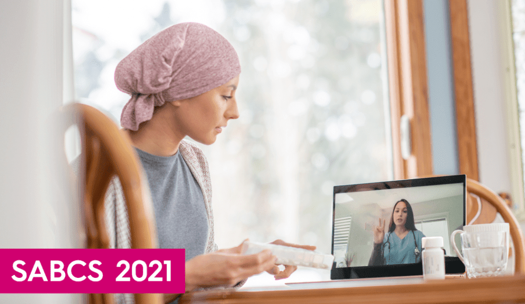 a woman with cancer wearing a headscarf talks to a doctor from home on her ipad