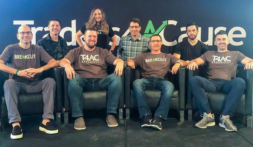 members of traders4acause pose at a previous conference wearing shirts with their logo