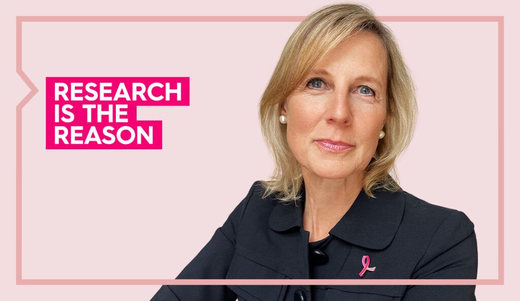 Dr. Irwin wears a black blazer and smiles at the camera against a light pink background