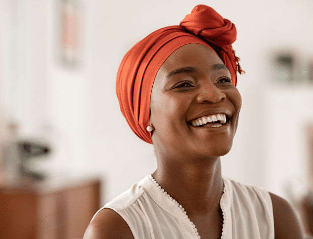 a young black woman smiles wearing an orange scarf on her head