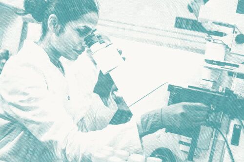 a pathologist looks at a microscope