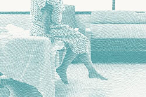 A woman wearing a hospital gown waits for a procedure