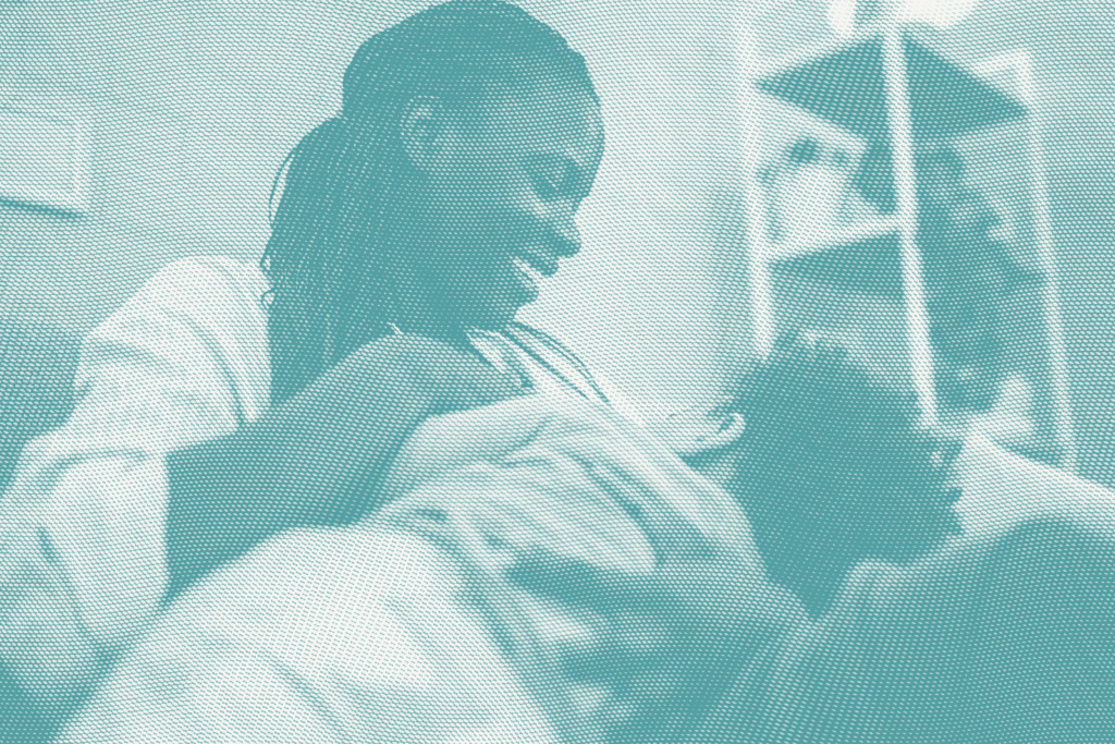 a woman breastfeeds her son, he's facing away from the camera and she's looking down smiling at him