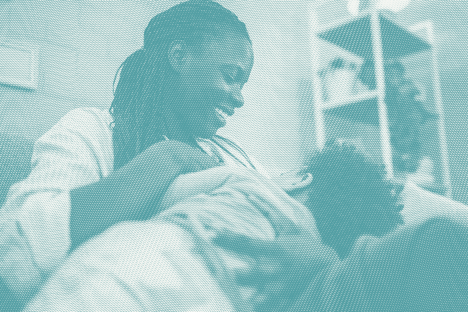 a woman breastfeeds her son, he's facing away from the camera and she's looking down smiling at him