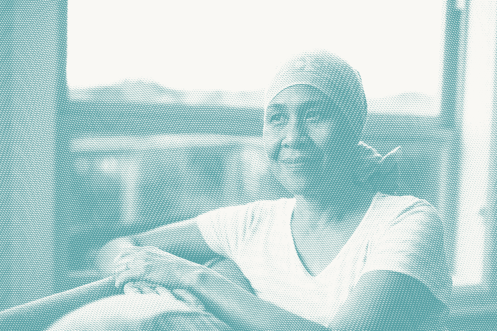 an older woman sits next to a window. she's wearing a headscarf as she's lost her hair after chemotherapy for breast cancer