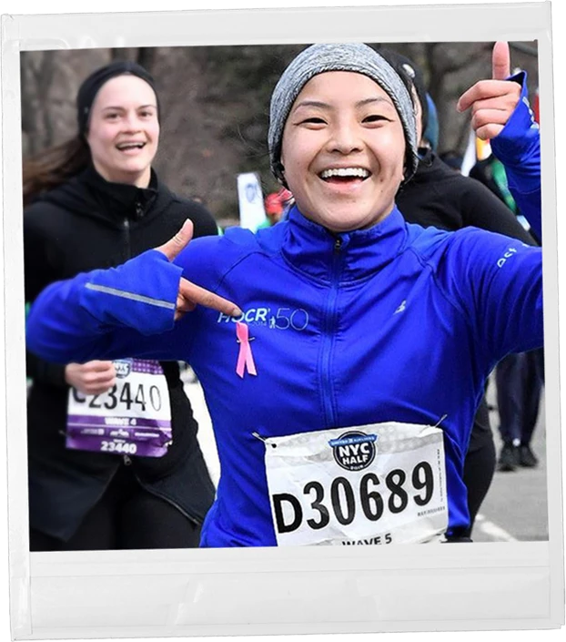 A Polaroid of a woman wearing a pink ribbon pin running a race.