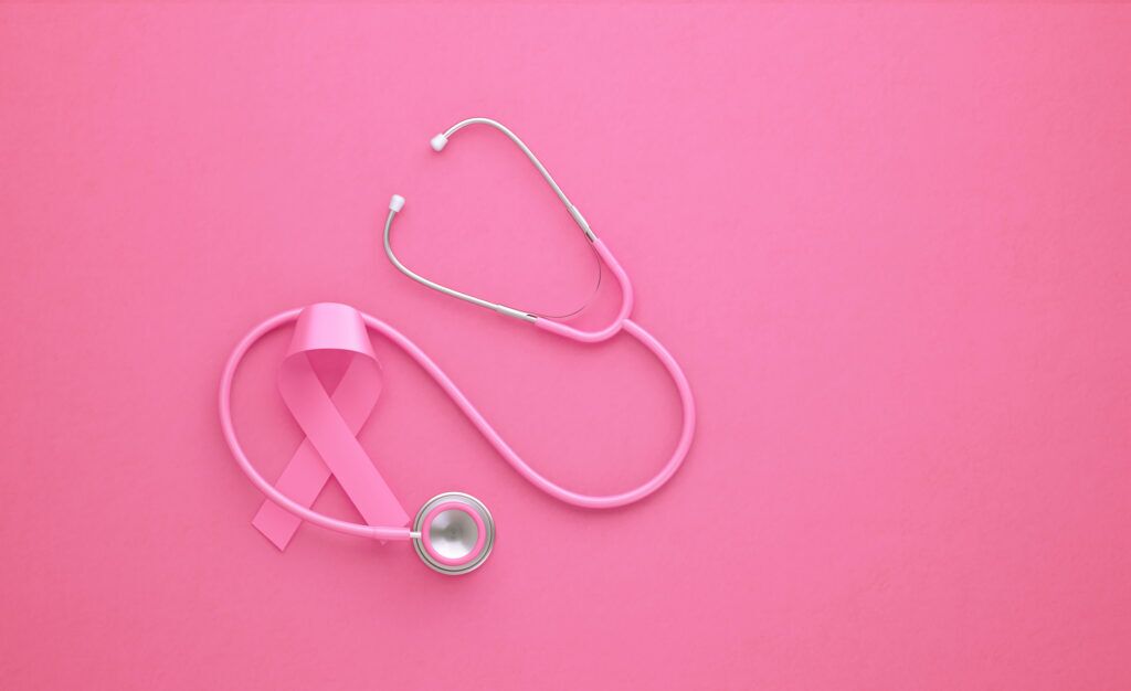 A pink ribbon is interspersed with a pink stethoscope against a pink background