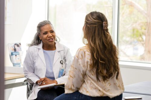 woman with her back turned talking to her doctor
