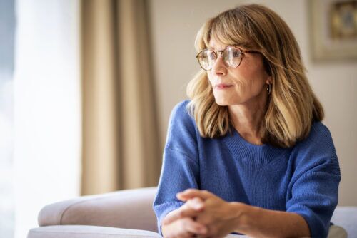 A woman wearing a blue shirt looks off into the distance.